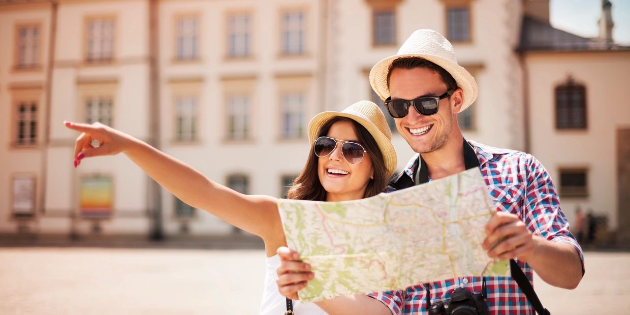 Happy tourist couple holding map in Europe.