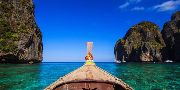 Traditional wooden longtail taxi boat at Maya Bay beach in transparent water of Indian Ocean, Ko Phi