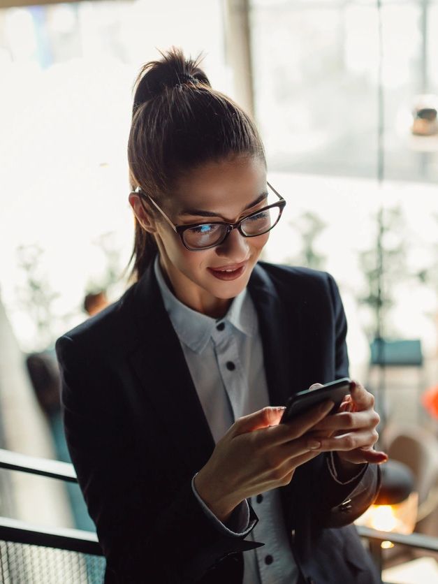 Woman with glasses smiling at her phone.