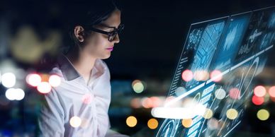 Woman with glasses viewing a virual floating screen as part of cloud hosting management