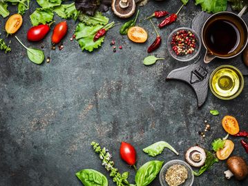 Fresh vegetables and spices arranged around a dark surface.