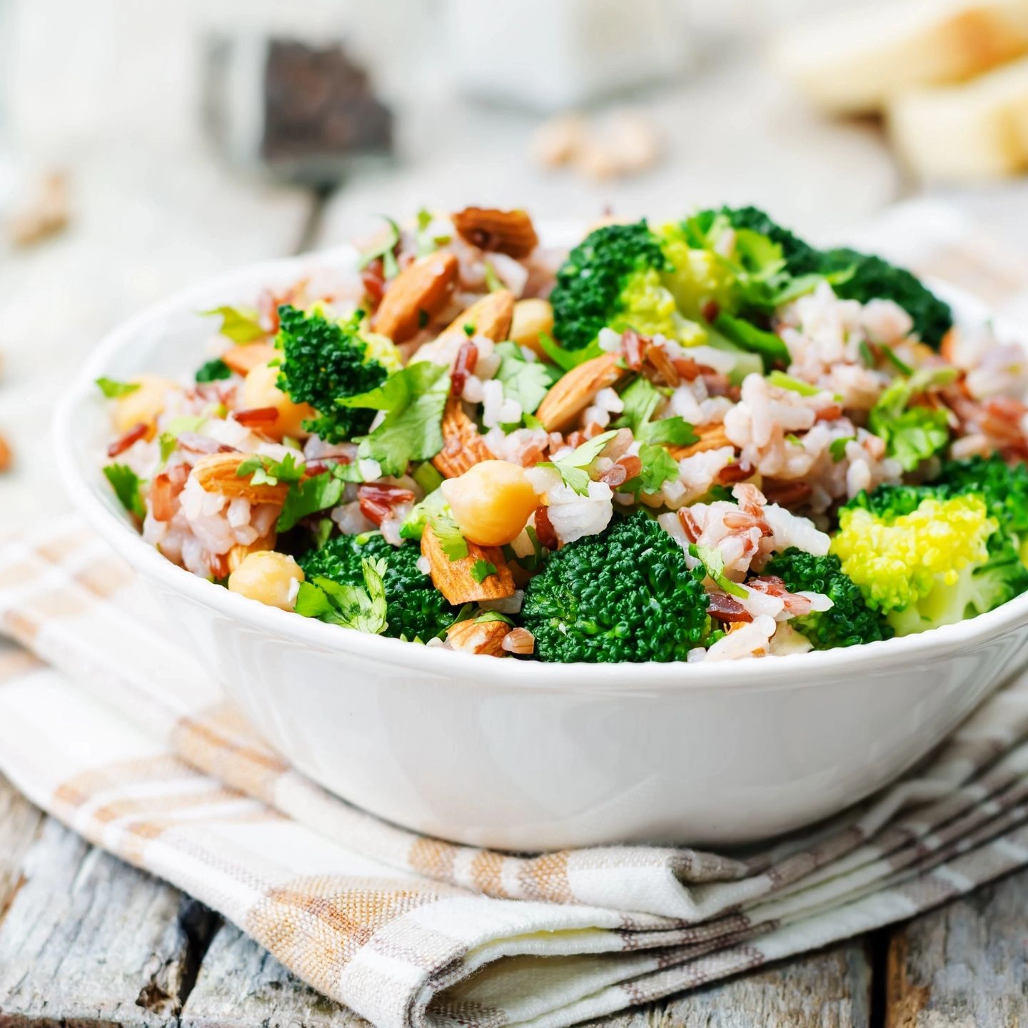 Healthy rice salad with broccoli, almonds, and chickpeas in a white bowl.