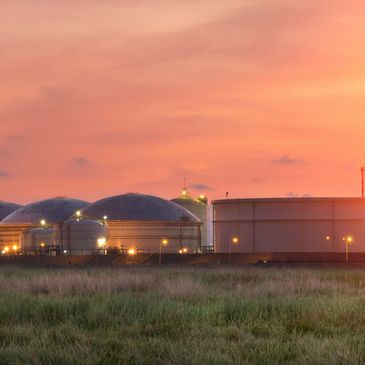 Industrial tanks at sunset with a vibrant orange sky.