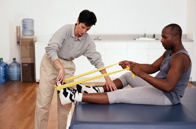 Physical therapist aiding a man with a leg exercise.
