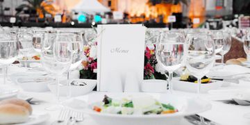 Elegant table setting with a menu and wine glasses at a formal event.