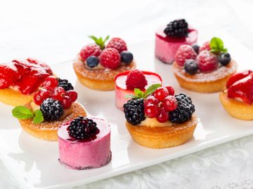 Assorted mini berry tarts and mousse desserts on a white plate.