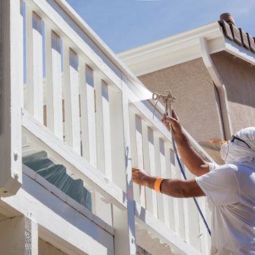 A man painting a building fence with a machine
