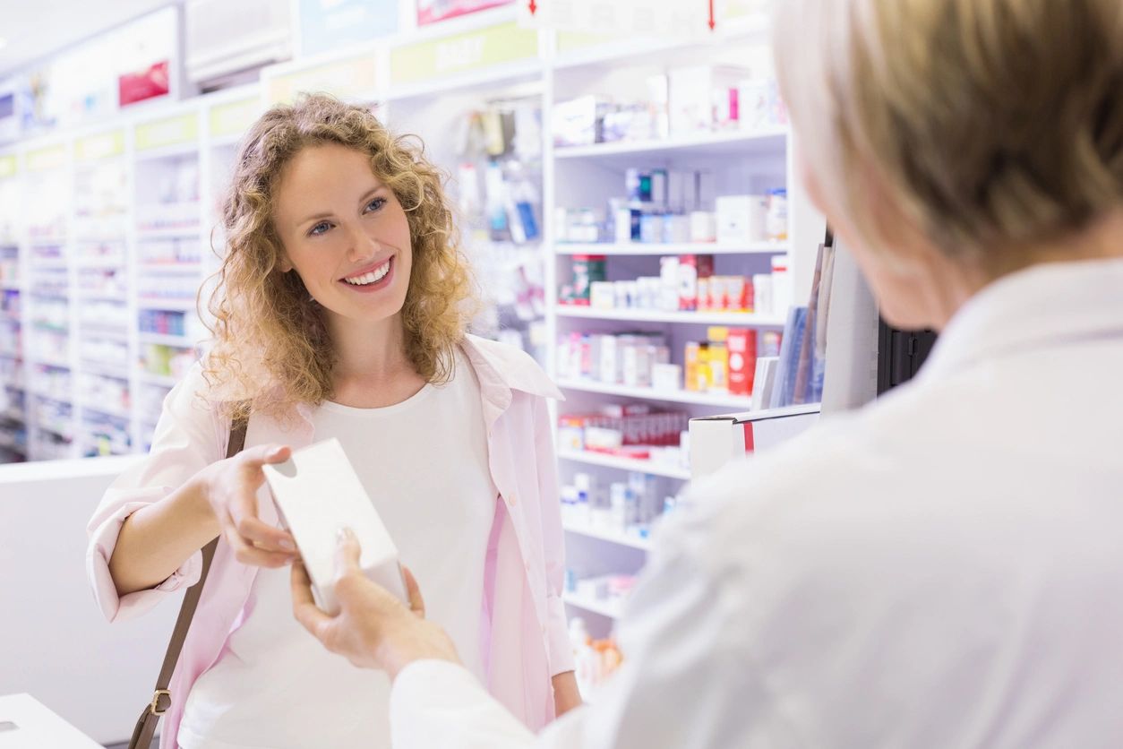 Lady being handed a package in a chemist store