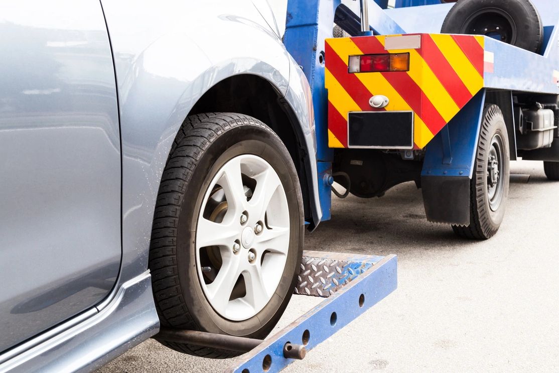 Close-up of a car wheel being loaded onto a tow truck.