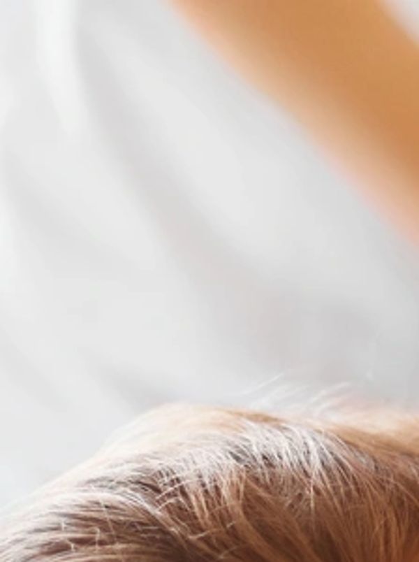 Close-up of light brown hair against a white background.