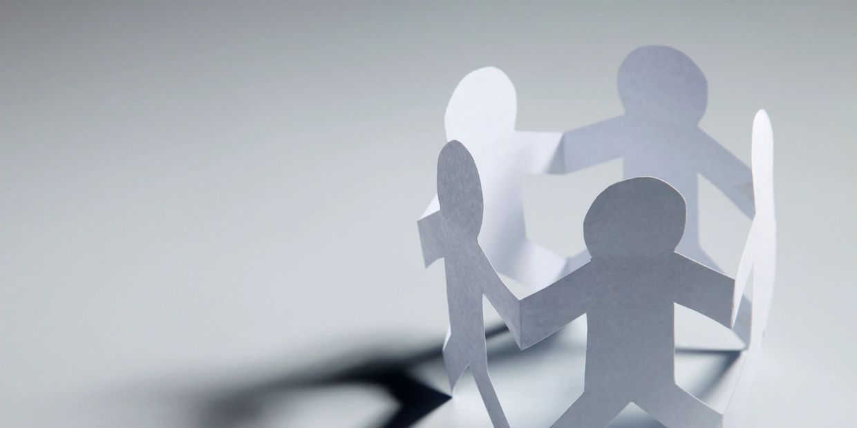 Paper cutout figures holding hands in a circle.