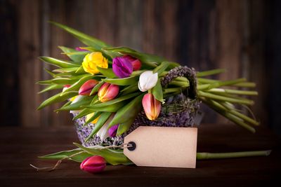 a bouquet of tulips with a blank gift tag in the foreground set against a brown paneling backdrop
