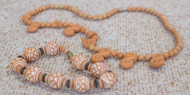Handmade clay necklace and bracelet on a fabric surface.