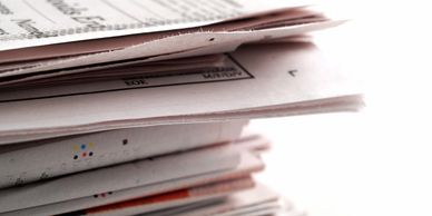 A close-up of a stack of newspapers with visible text and print details.