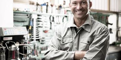 Smiling mechanic in work overalls in a workshop.