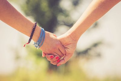 two people holding hands, one with painted nails and one with bracelets on