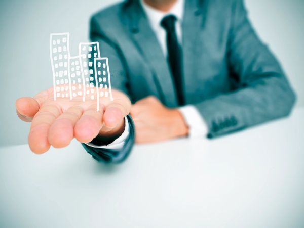 Businessman in suit holding a hand-drawn cityscape illustration.