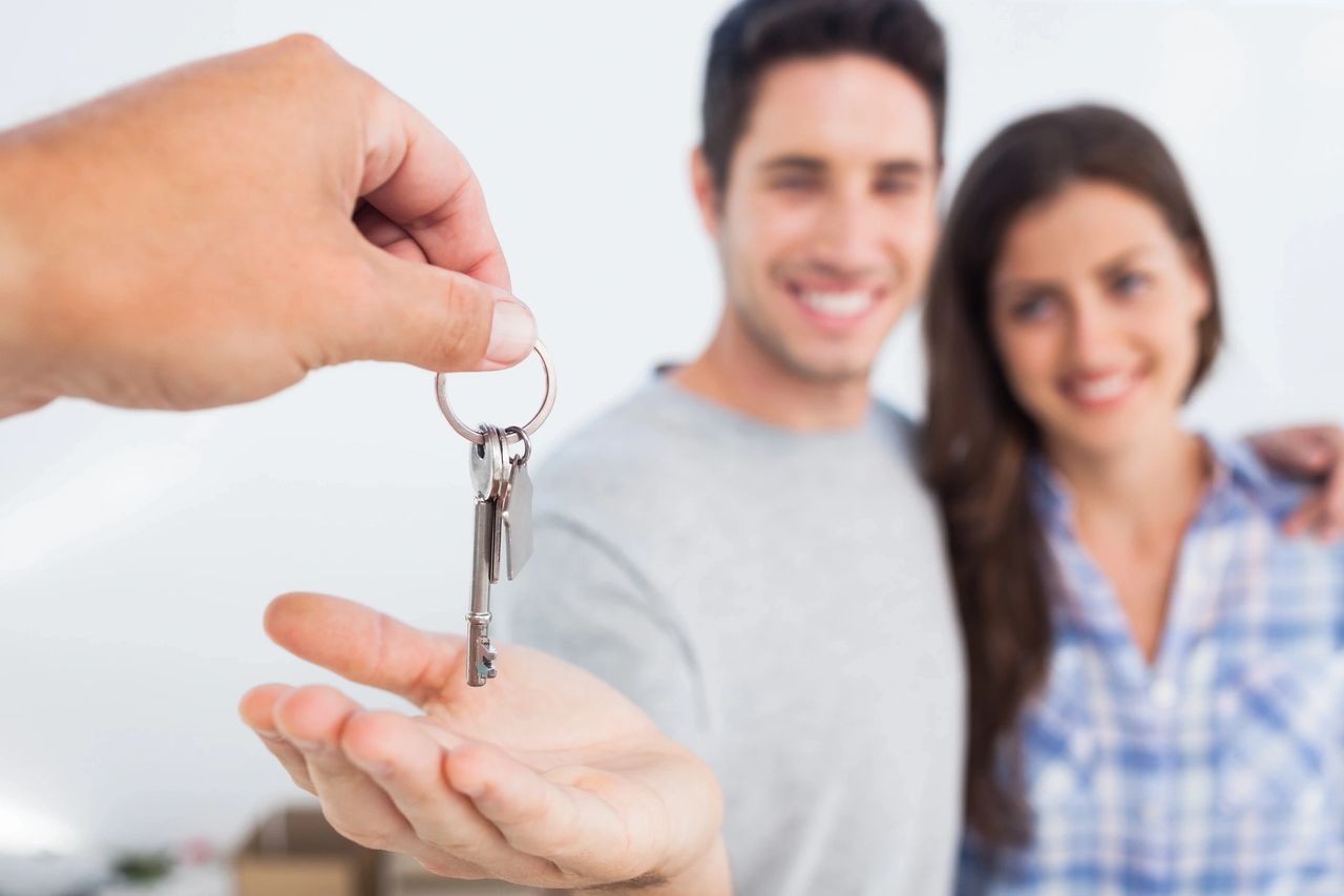 Home buyers smile as they receive the keys to their new home.