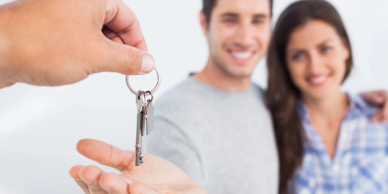 A couple is being handed the keys from a real estate agent to the new home they just purchased. 