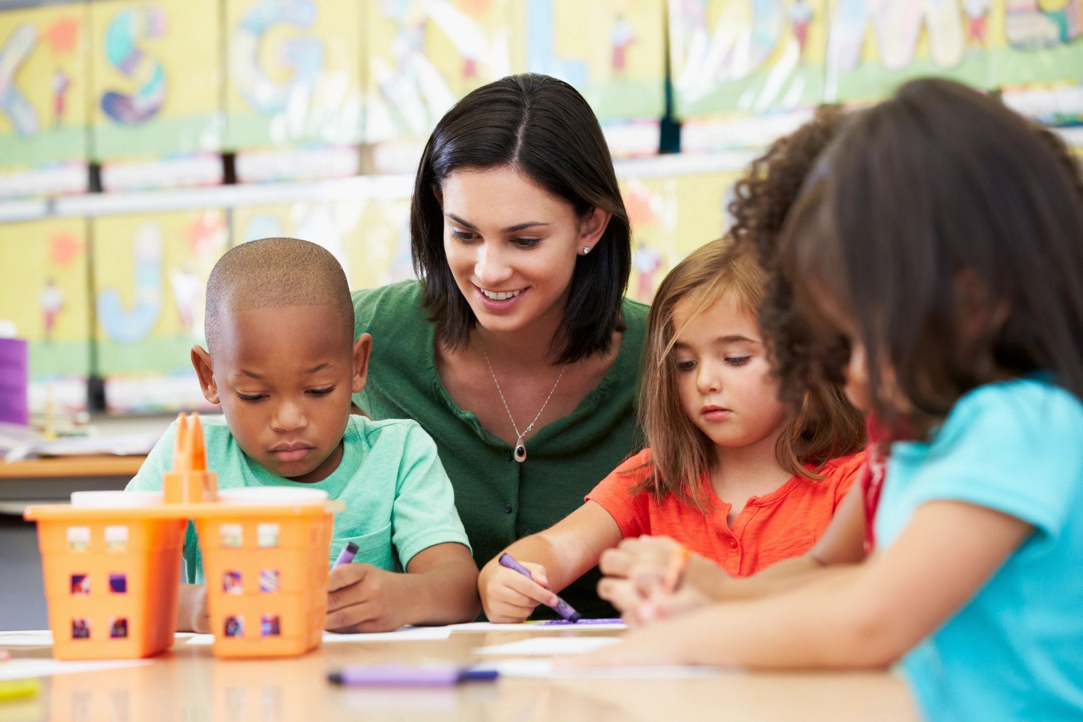 teacher helping young children use crayons