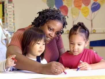 Teacher helping children with drawing activity.