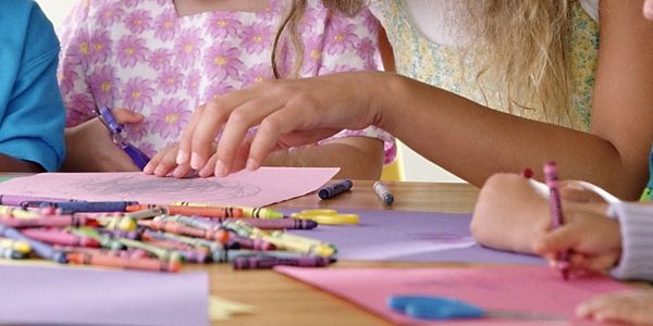 Children coloring with crayons at a table.