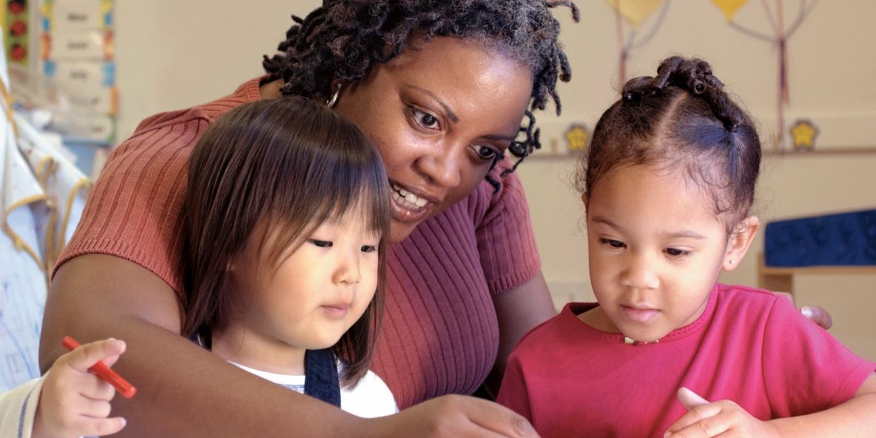 Educator sitting and working with two young children