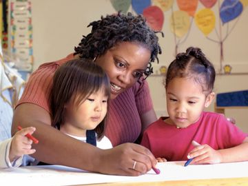 Teacher helping children color