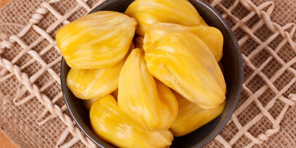 Fresh yellow jackfruit bulbs in a black bowl.