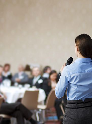 A woman is holding a microphone while standing in front of a group.