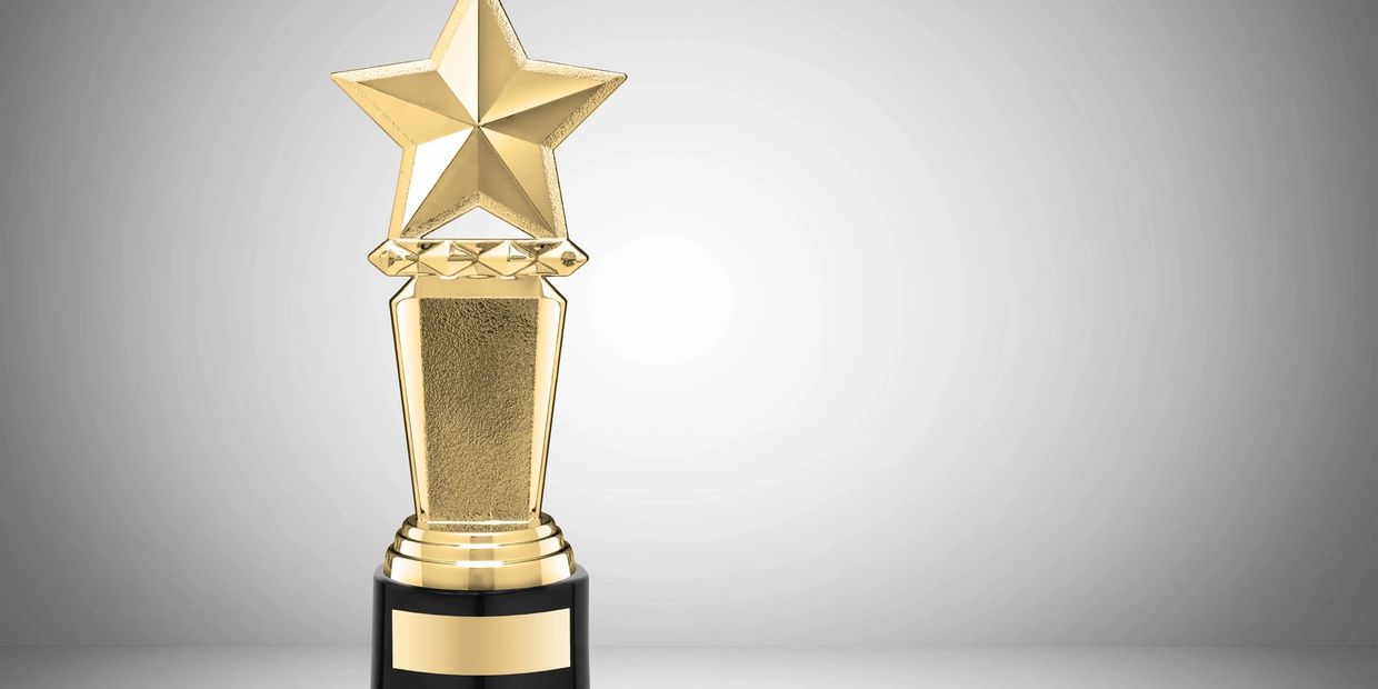 Golden star trophy on a black base against a gray background.