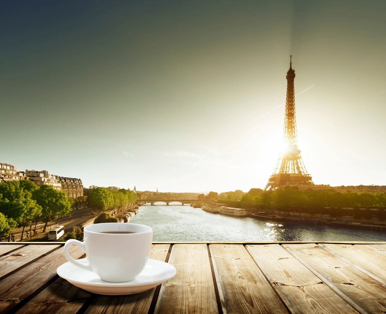 A cup of coffee with a sunset view of the Eiffel Tower.