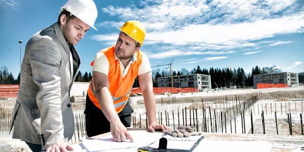 Project Manager Meeting with site manager at a custom home job site discussing plans from architect 