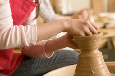 Person shaping clay on a pottery wheel.