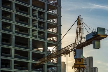 Construction cranes working on high-rise buildings during sunset.
