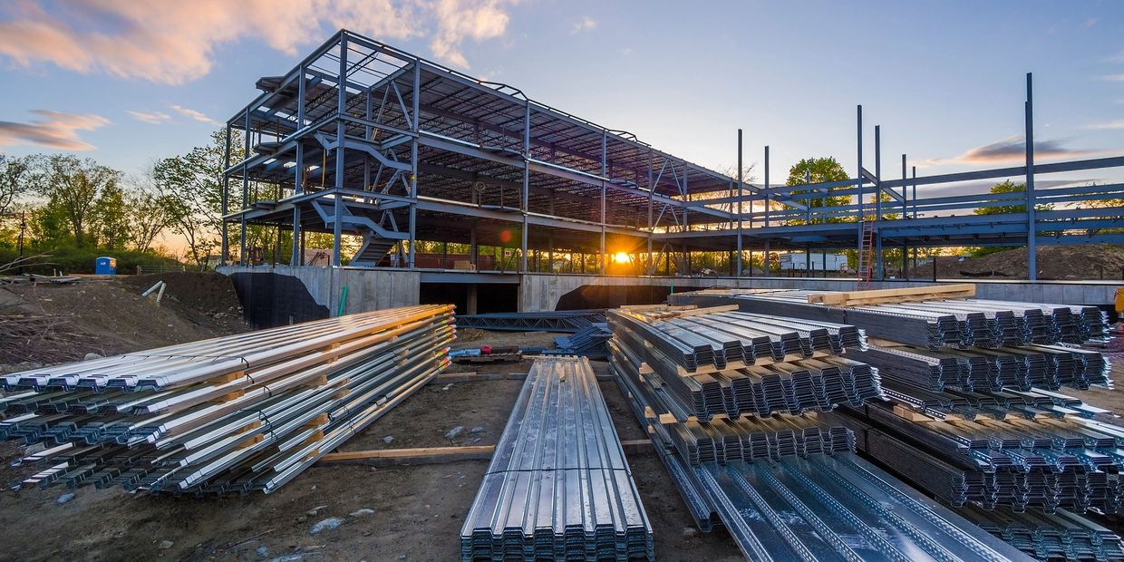 Steel structure building under construction at sunset.