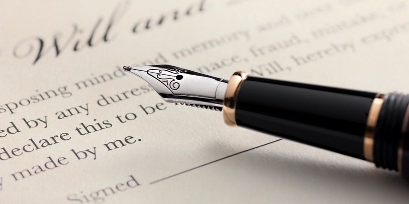 A fountain pen resting on a will and testament document.
