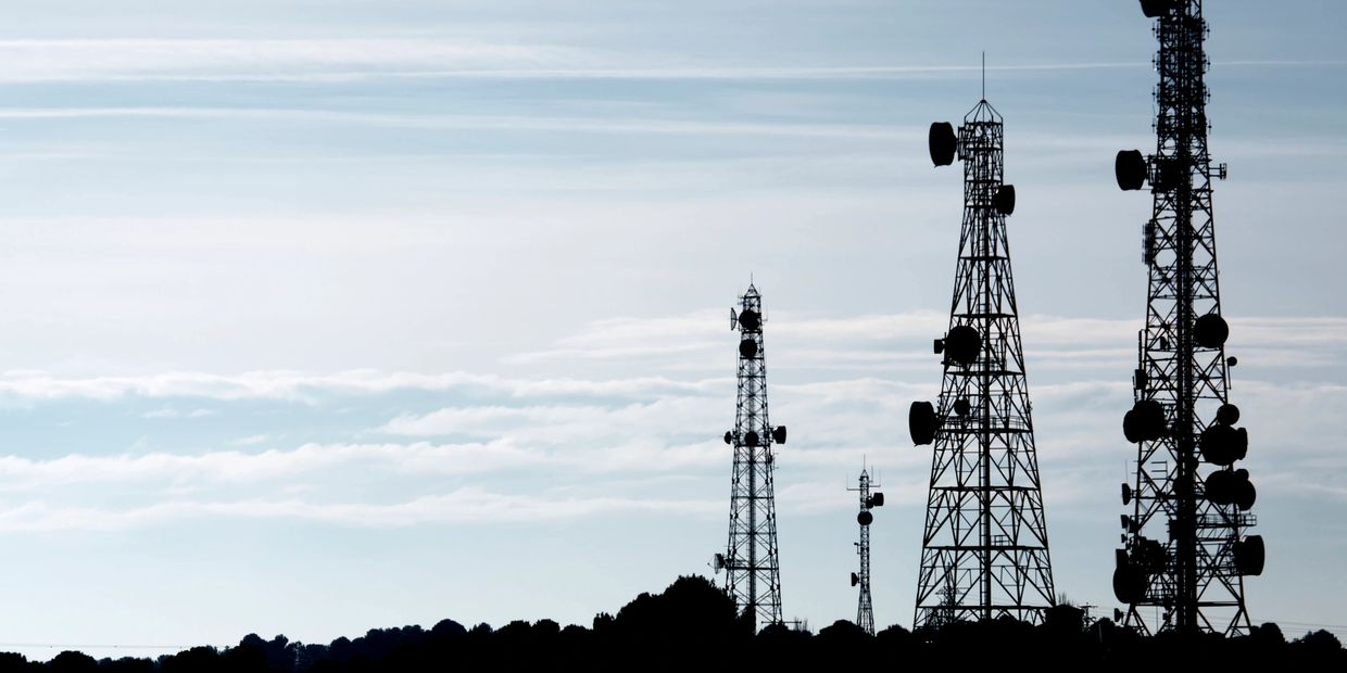Silhouettes of communication towers against a cloudy sky.