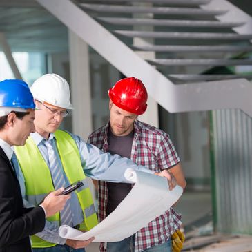 Three construction workers wearing blue, white, and red helmets