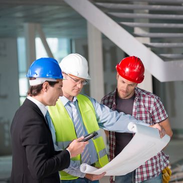 Three construction professionals reviewing blueprints on site.