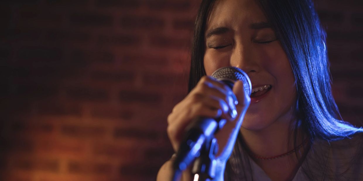Young woman passionately singing into a microphone.