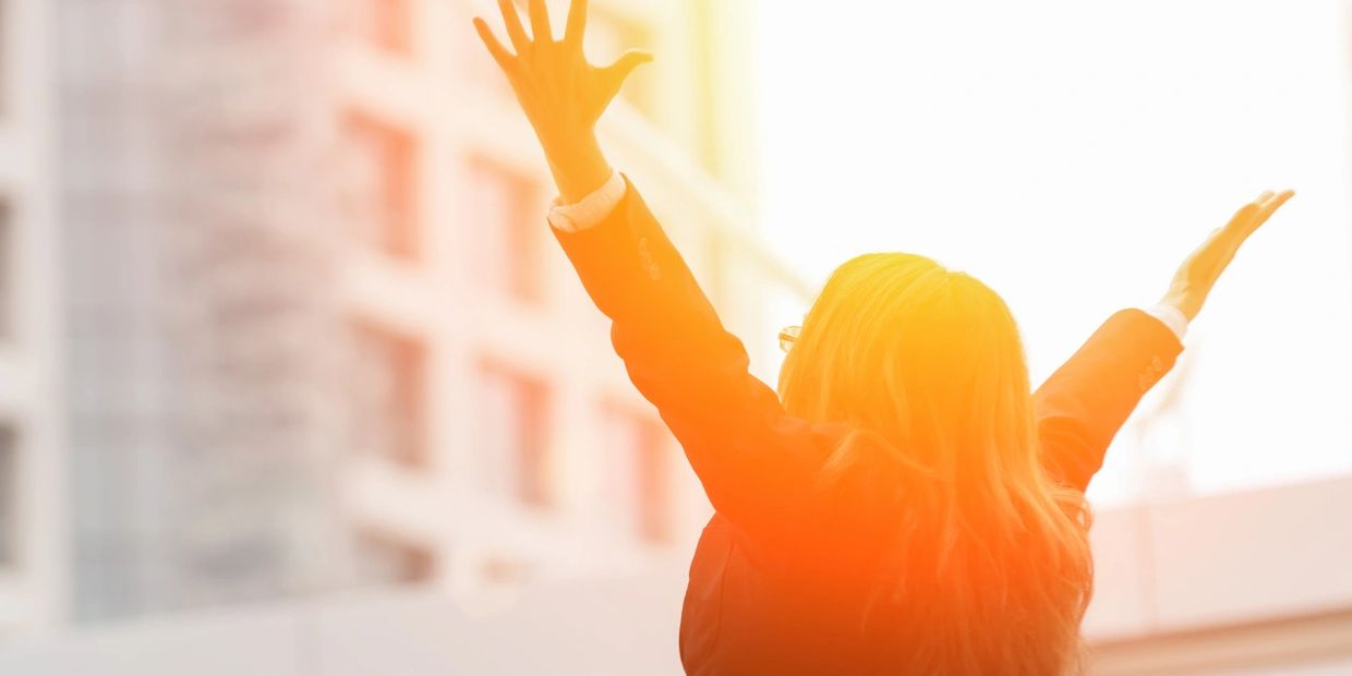 female with hands raised to sky 