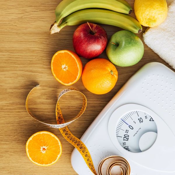 Healthy fruits, measuring tape, and weighing scale representing fitness and diet.