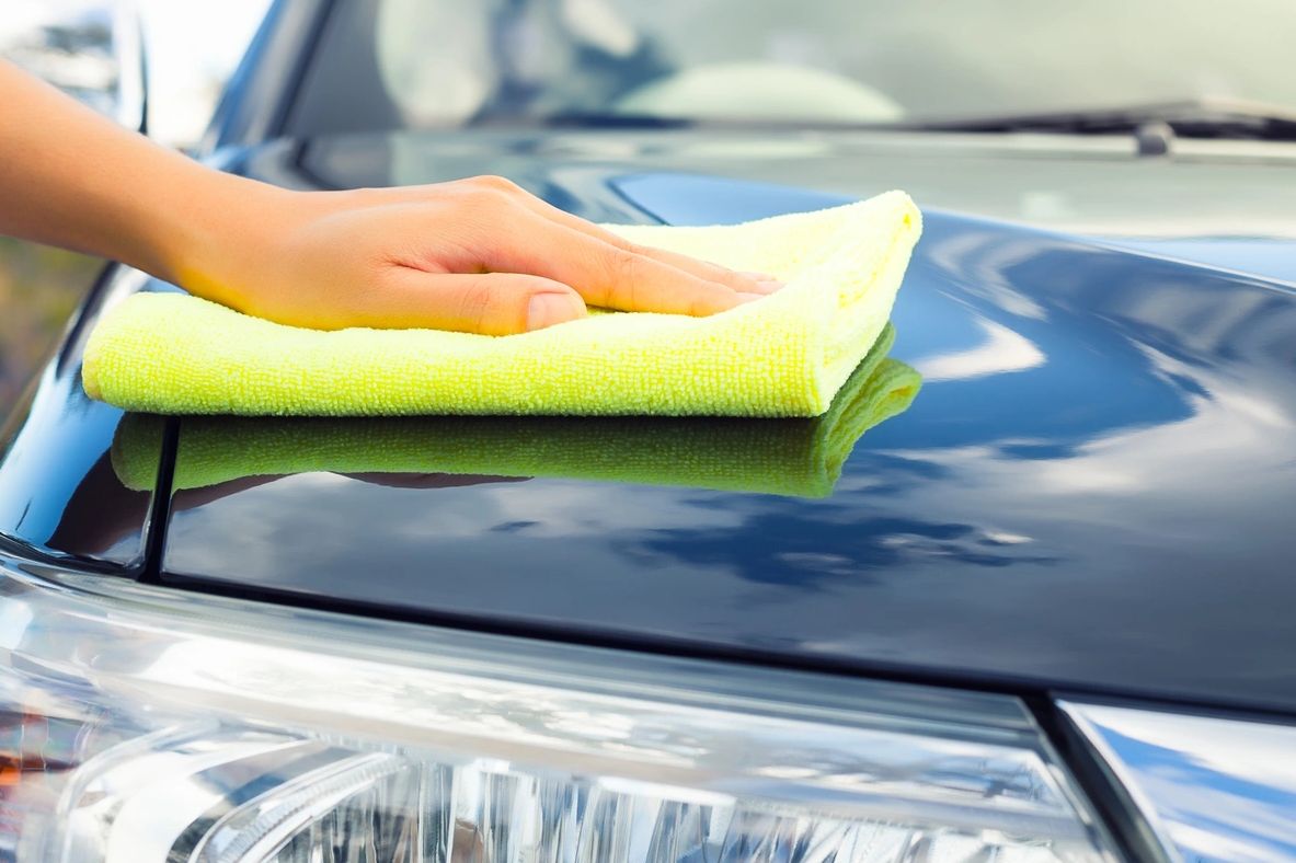 A picture of a person polishing a cars front body