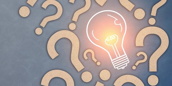 Light bulb glowing among question marks.