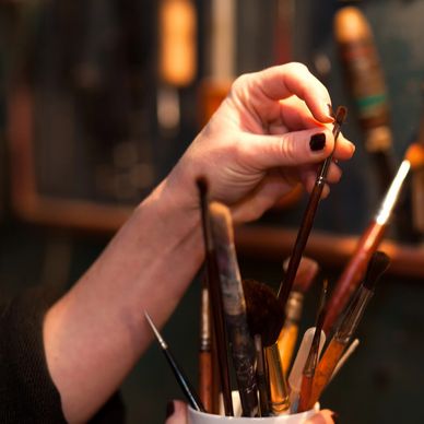 Hand selecting a paintbrush from a collection.