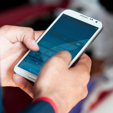 Person typing on a white smartphone with a blue screen.