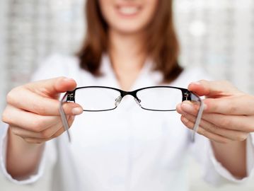 Person holding eyeglasses forward.