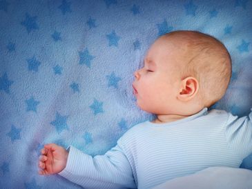Peaceful baby sleeping on a blue star-patterned blanket.
