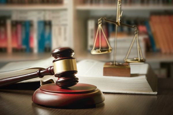Judge's gavel, scale of justice, and open book on desk.